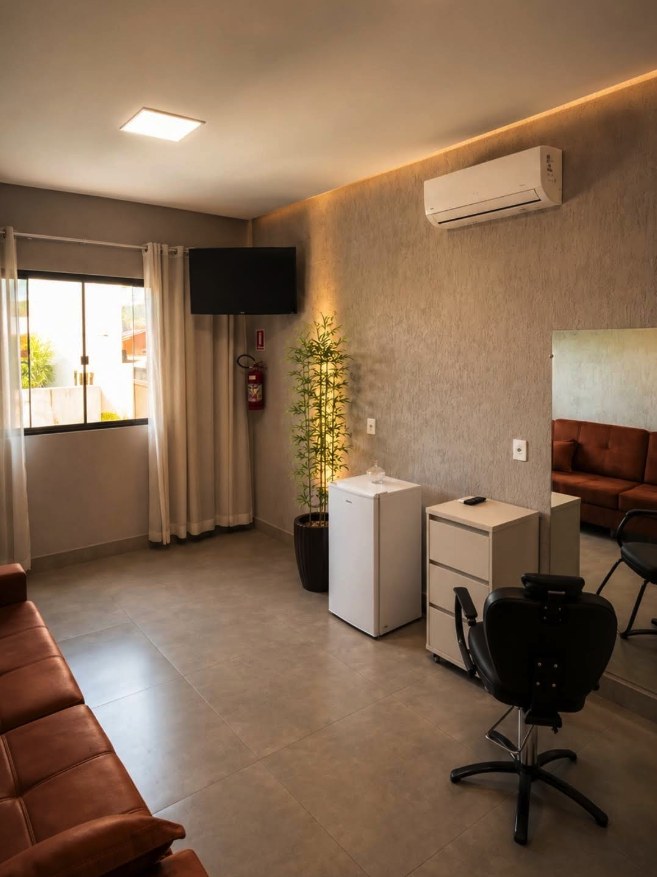 Camarim com suíte da Dream House Eventos em Goiânia, com sofá, espelho, cadeira de produção, frigobar, televisão e ar-condicionado