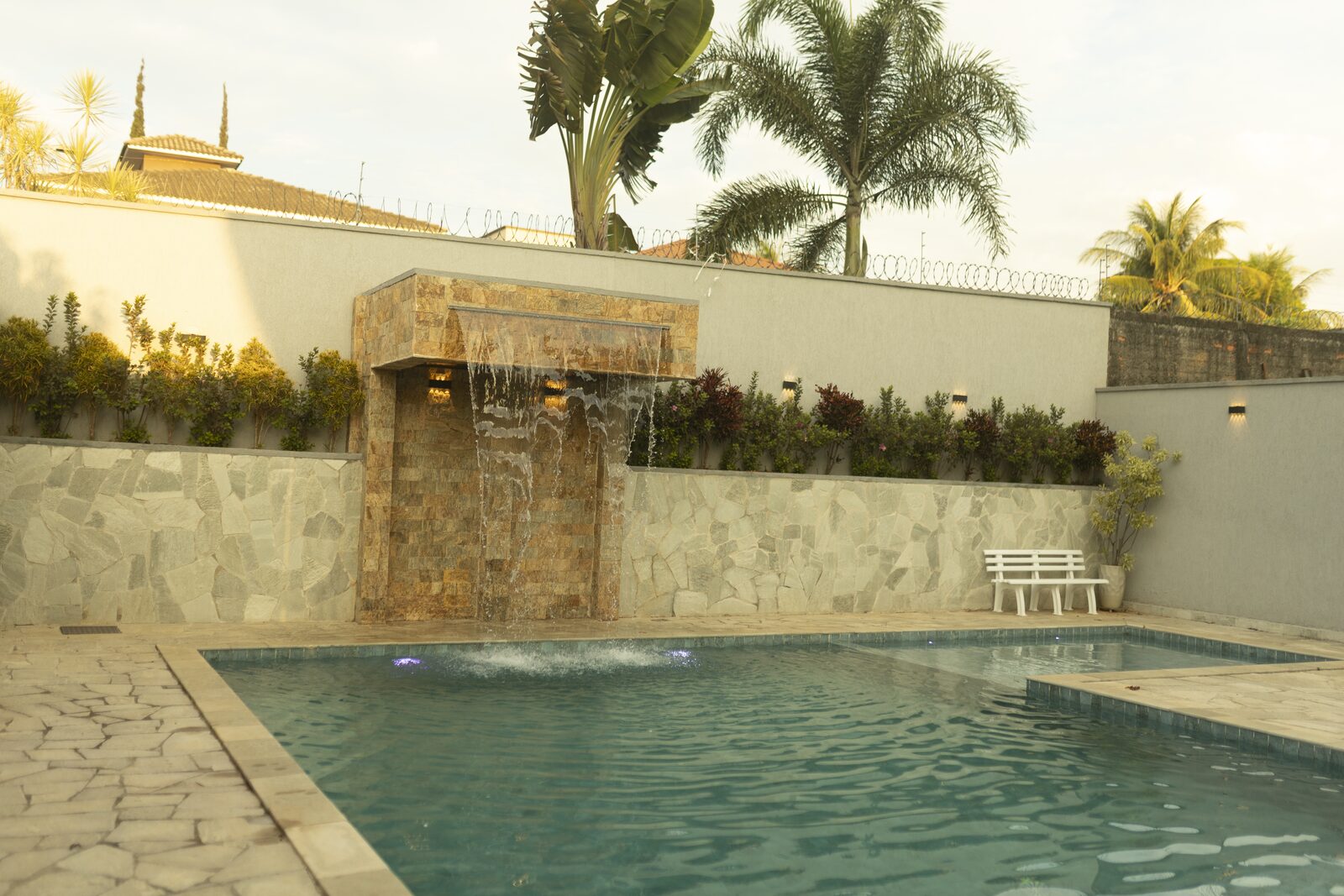 Área externa com piscina e cadeiras de sol durante o dia na Dream House Eventos