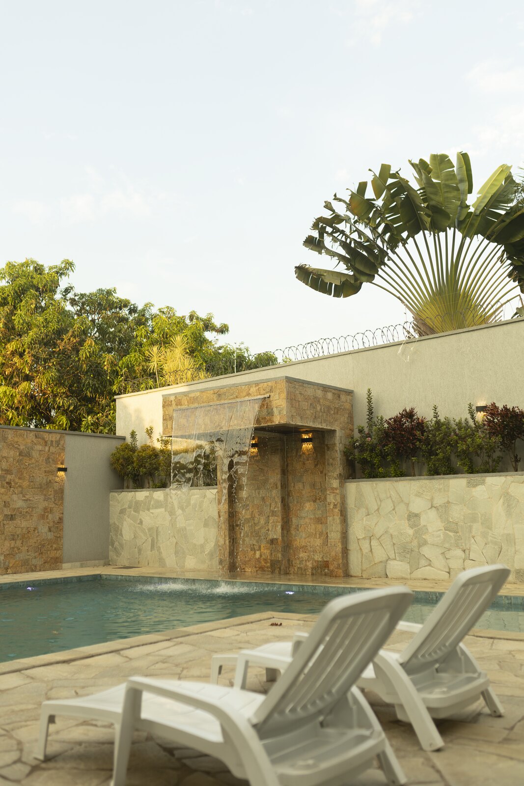 Piscina com espreguiçadeiras na área externa da Dream House Eventos
