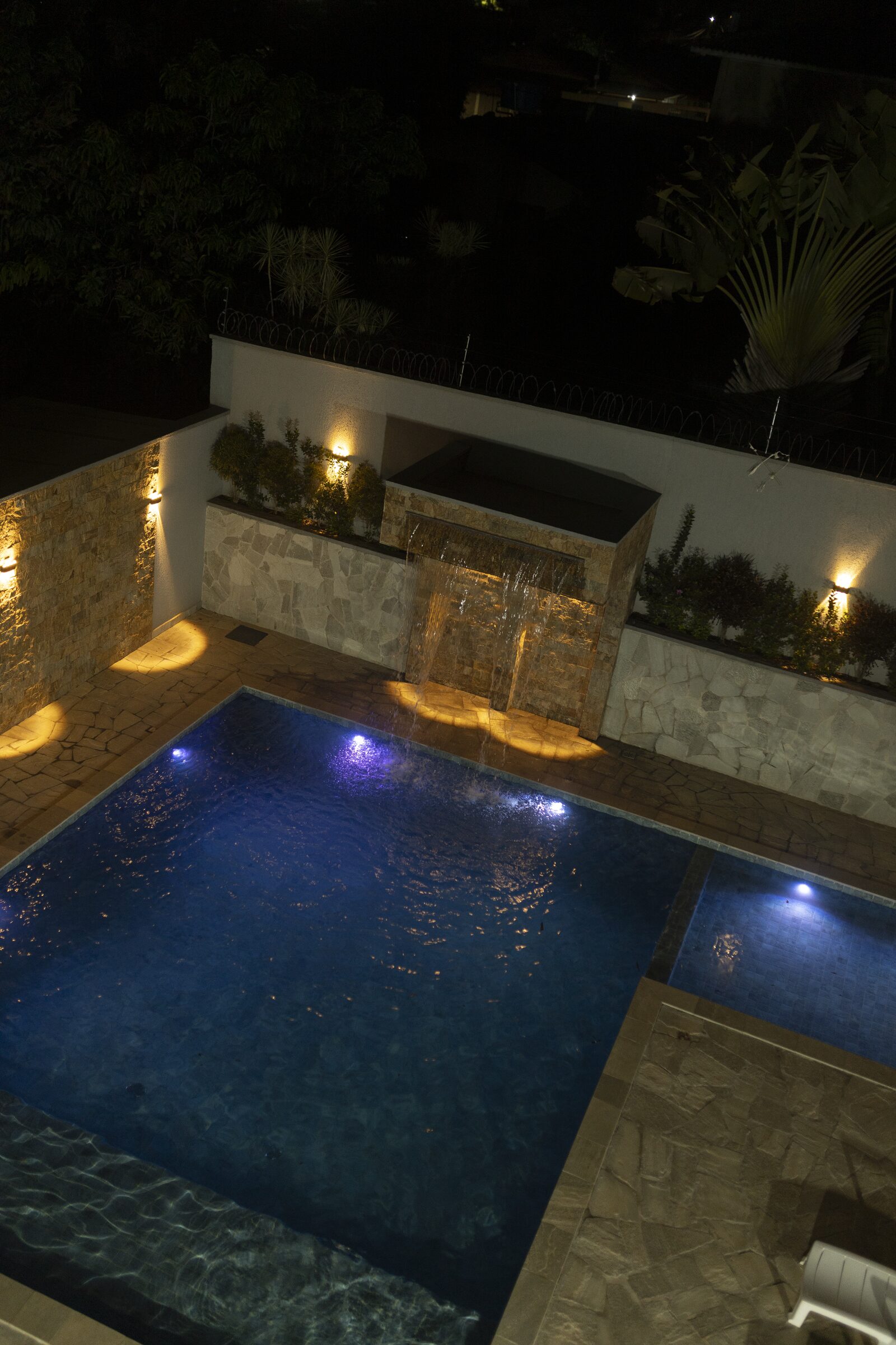 Piscina iluminada à noite na Dream House Eventos
